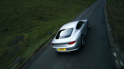 a silver sports car driving down a country road