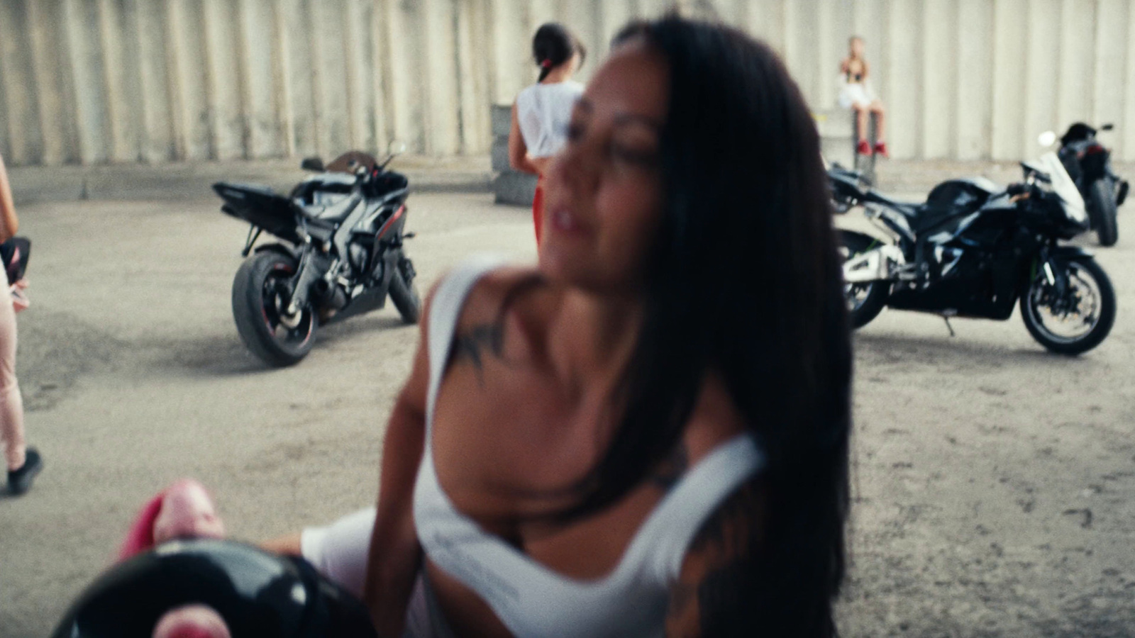 a woman in a white tank top standing in front of a group of motorcycles