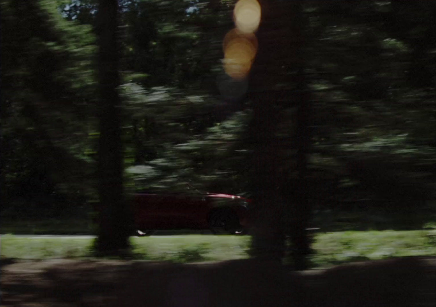 a blurry picture of a red car in the woods