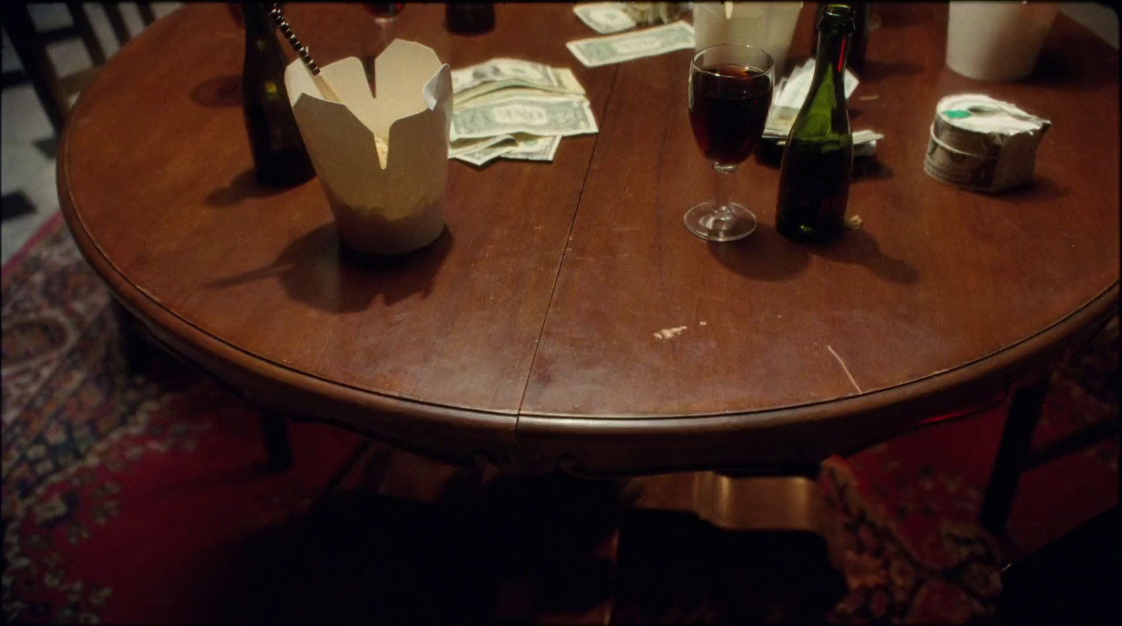 a wooden table topped with bottles of wine and money