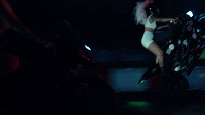 a woman riding on the back of a motorcycle at night