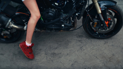 a woman in red shoes sitting on a motorcycle