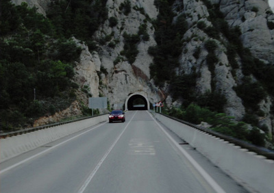 a car driving through a tunnel on a mountain road