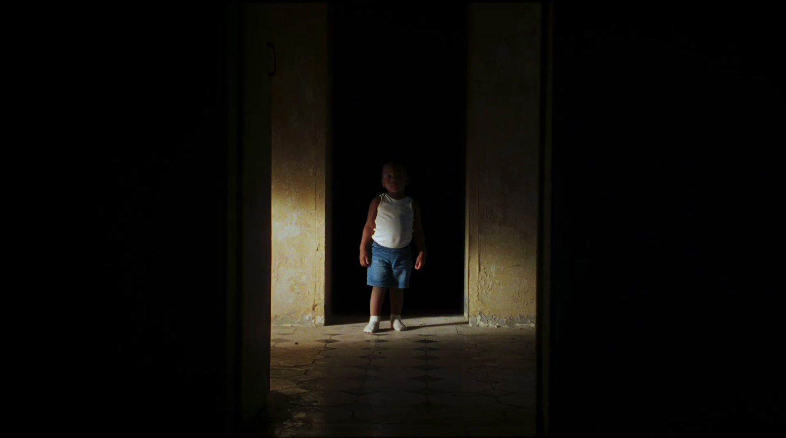 a young boy standing in a doorway at night