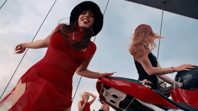 a woman in a red dress standing next to a red motorcycle