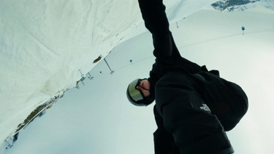 a man riding a snowboard down the side of a snow covered slope