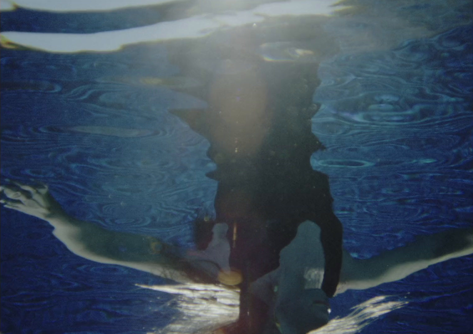 a woman swimming in a pool with her reflection in the water