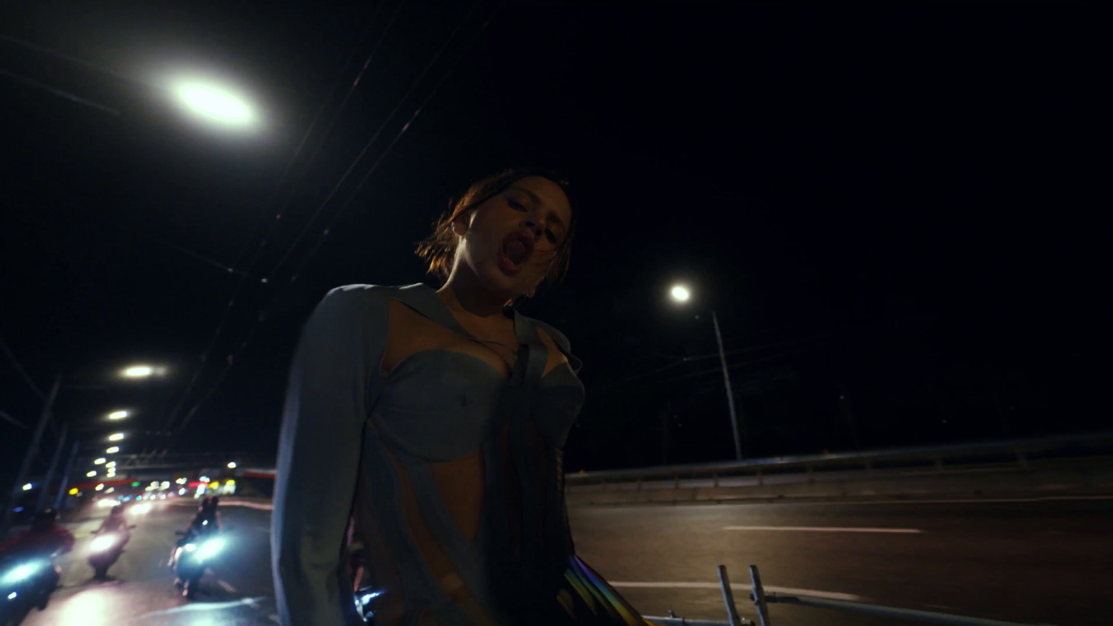 a woman standing on the side of a road at night