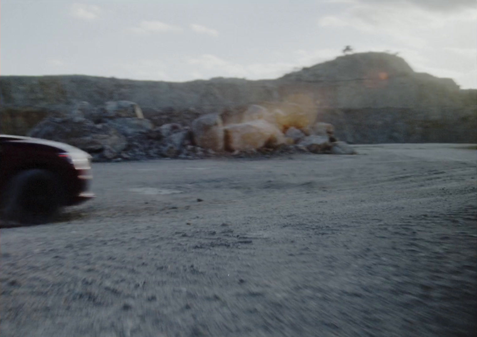 a car driving down a road next to a rock wall