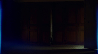 a dark room with a blue light coming through the doorway