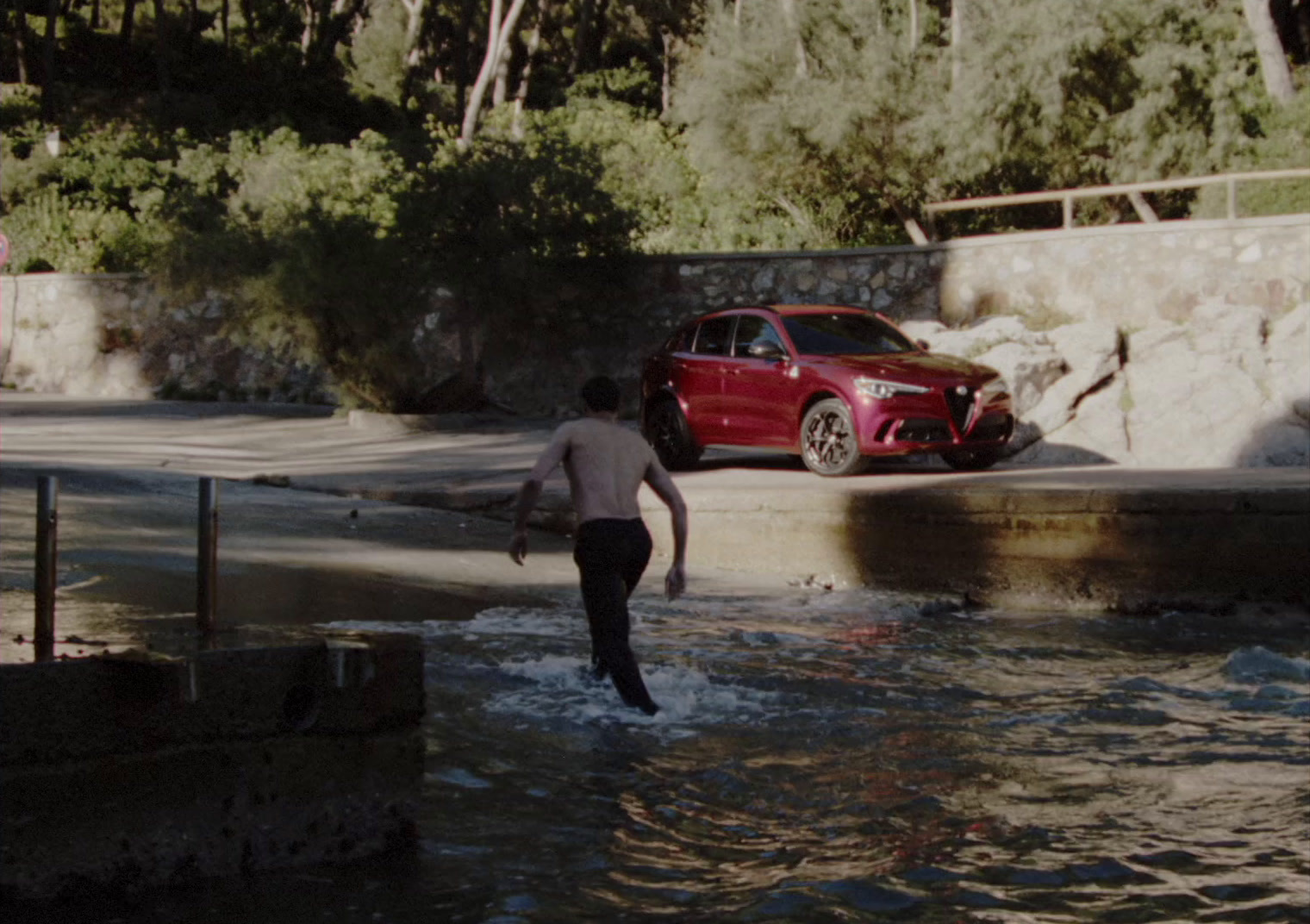 a man is walking in the water near a red car