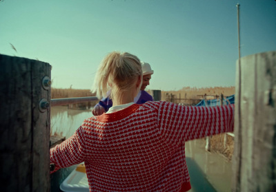 a woman in a red and white sweater standing next to a pole