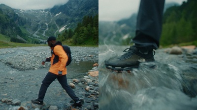 a man walking across a river next to a forest