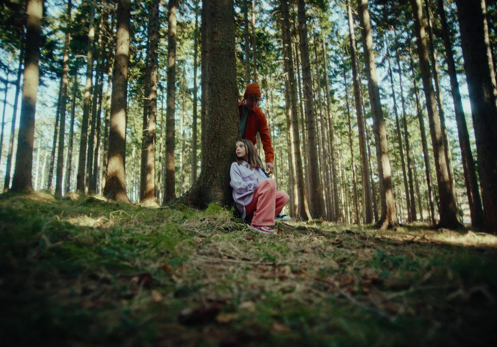 a man and a woman sitting on the ground in the woods