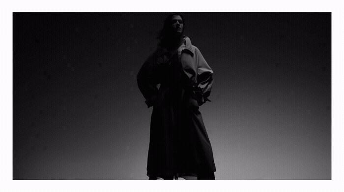 a black and white photo of a woman in a trench coat