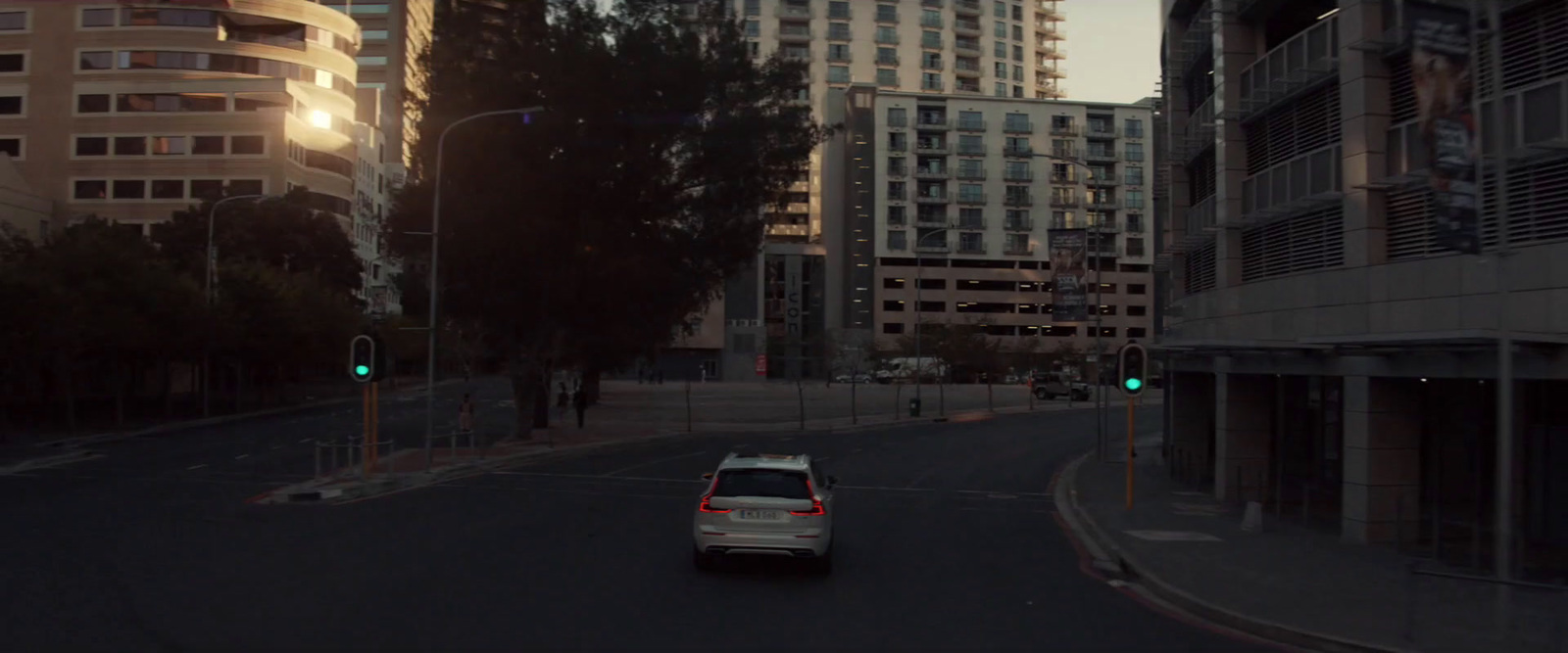 a white car driving down a street next to tall buildings