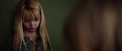 a little girl with long blonde hair standing in front of a mirror