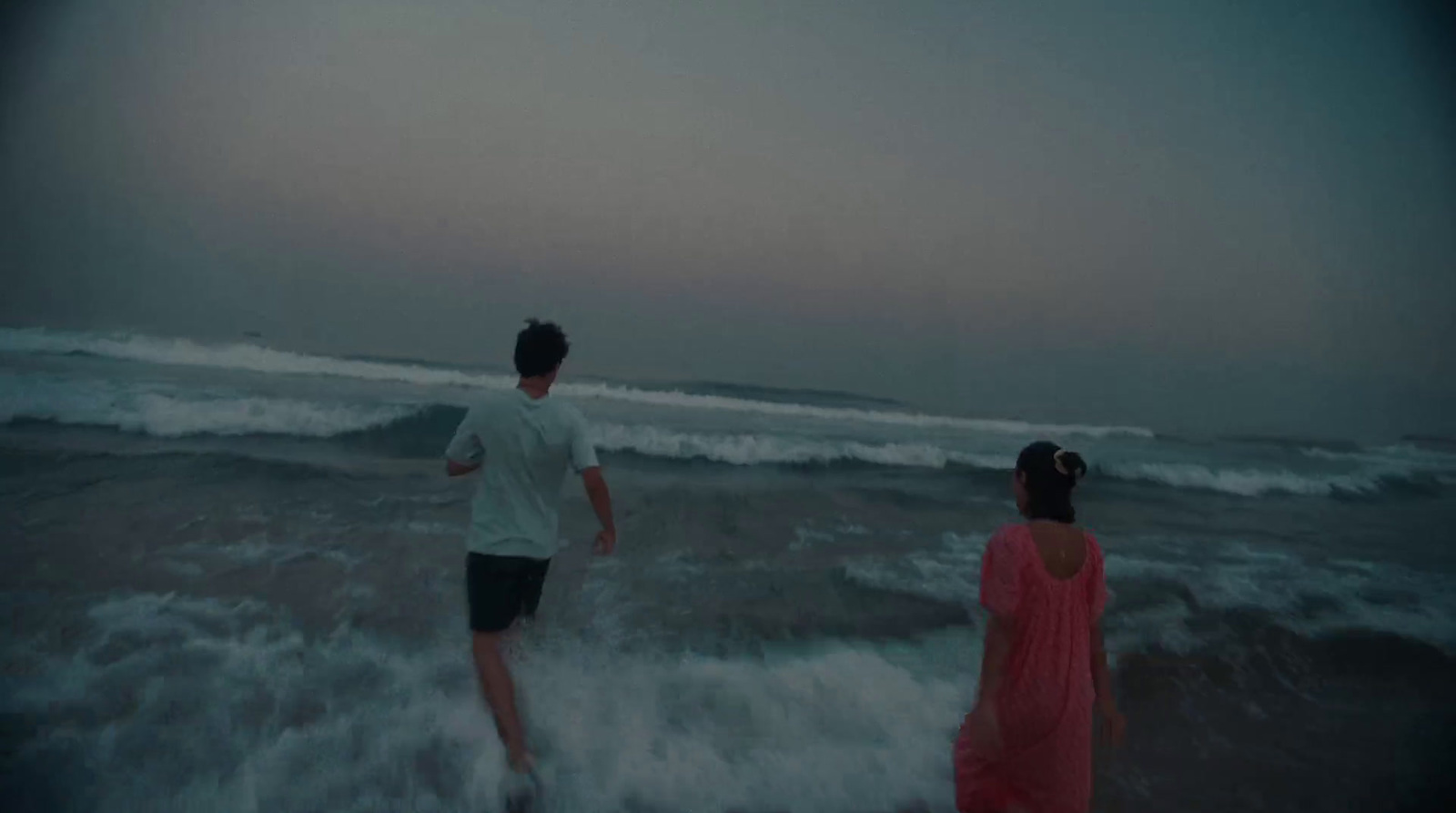 a man and a woman walking into the ocean