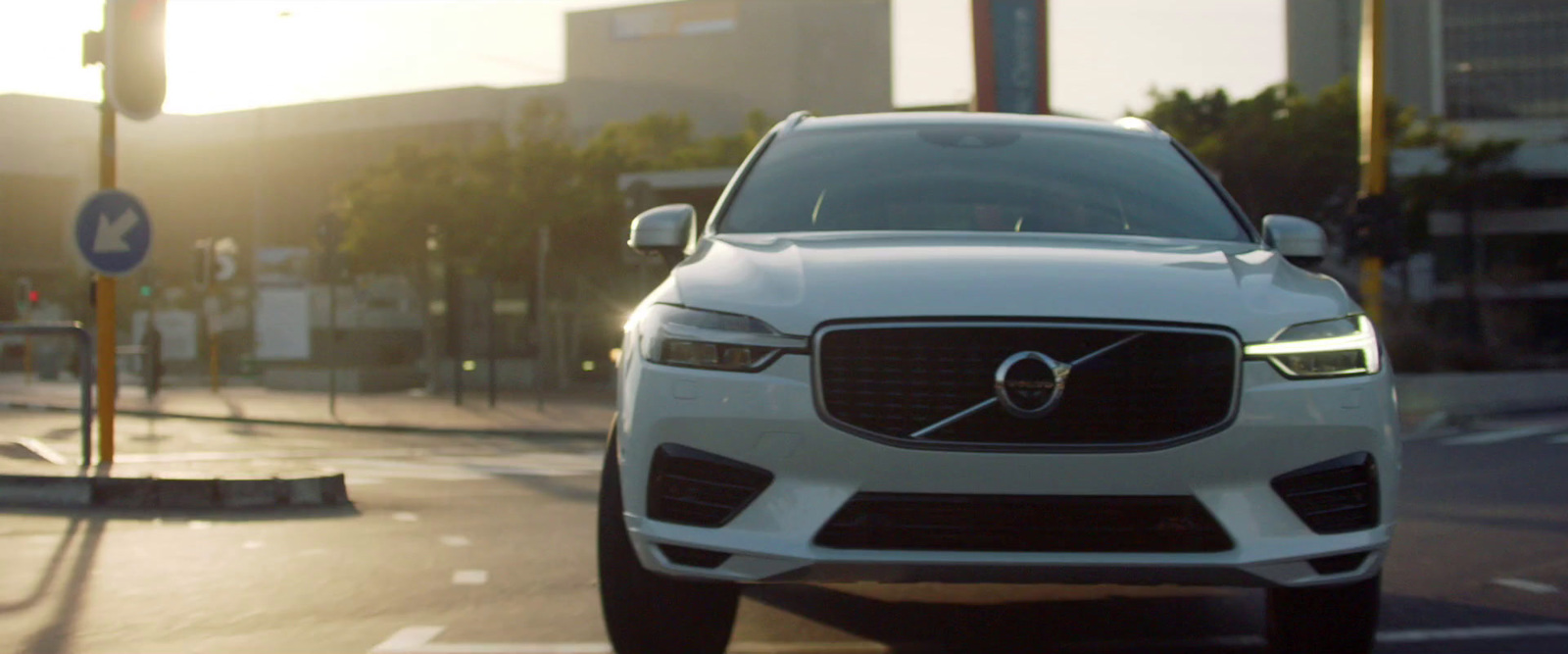 a white volvo car driving down a city street