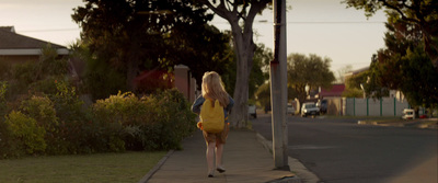 a woman in a yellow dress walking down a sidewalk