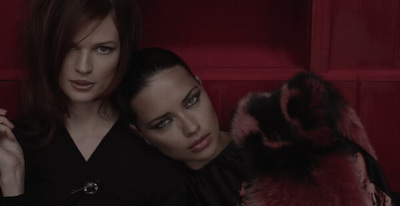 two women sitting next to each other on a red couch