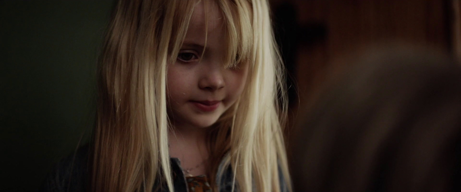 a little girl with long blonde hair standing in front of a mirror