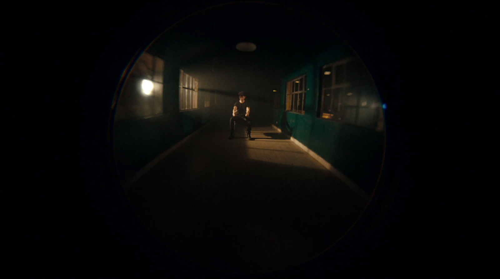 a person sitting on a bench in a dark hallway