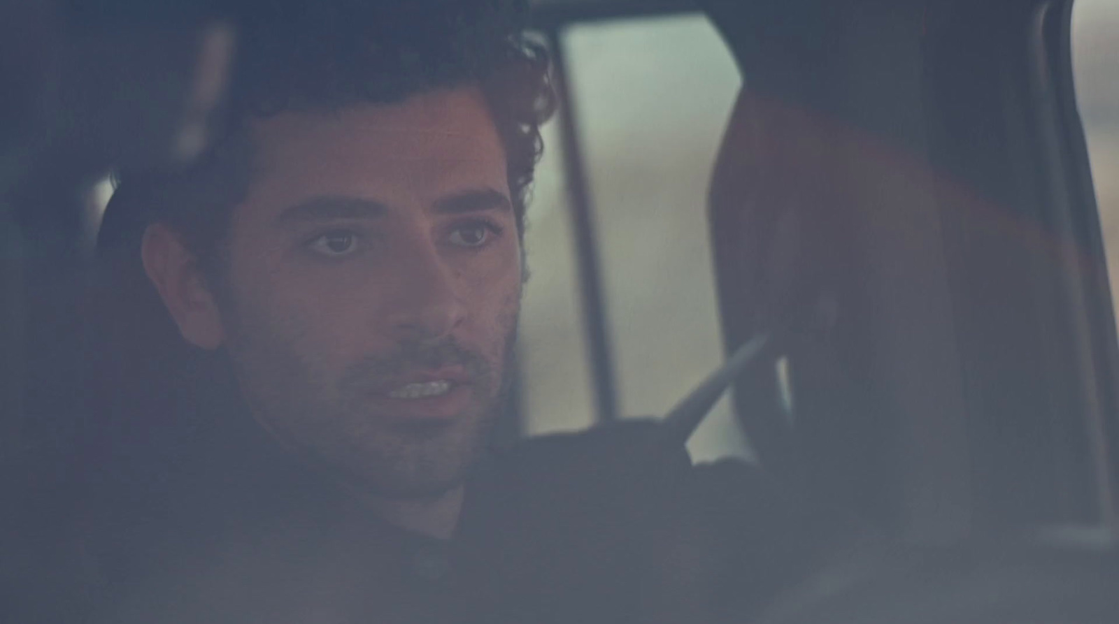 a man sitting in a car looking out the window