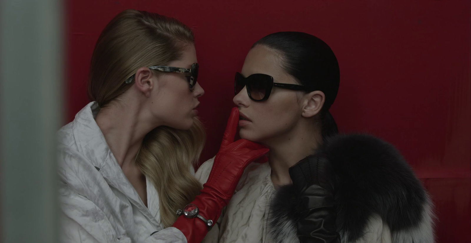 two women in white coats and red gloves looking at each other