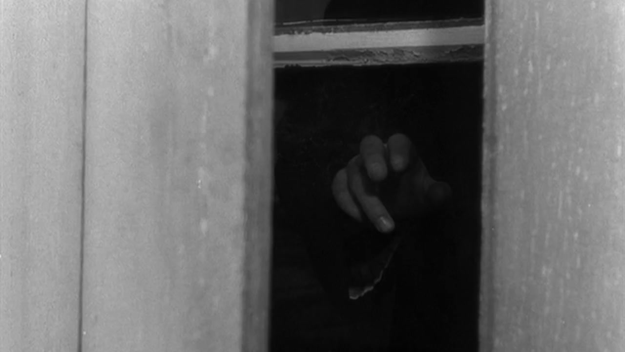 a black and white photo of a person's hand coming out of a window