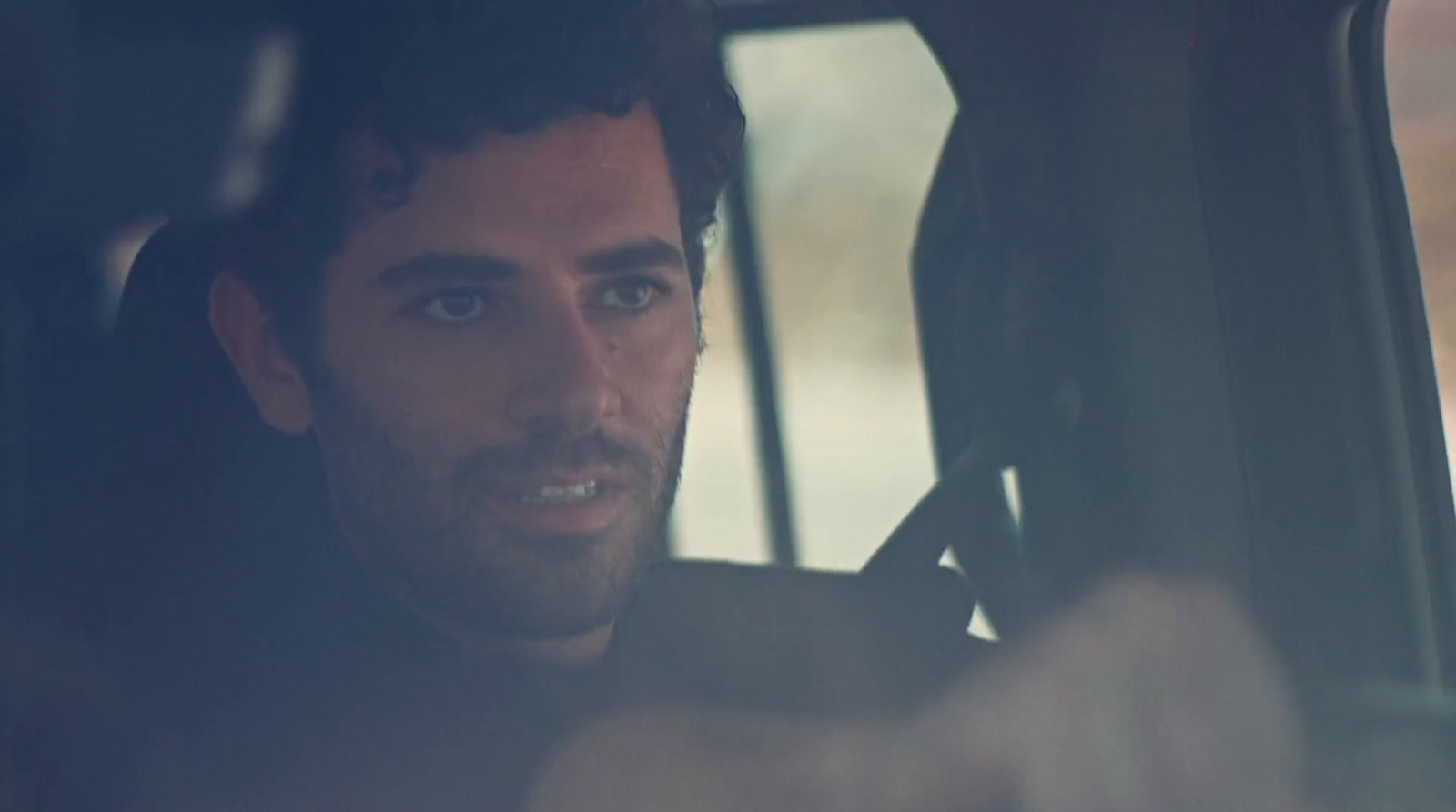 a man sitting in a car looking out the window