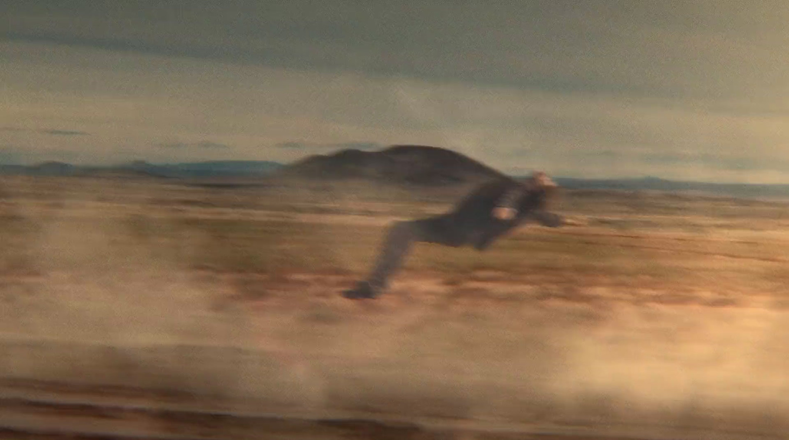 a man riding a skateboard on top of a dry grass field