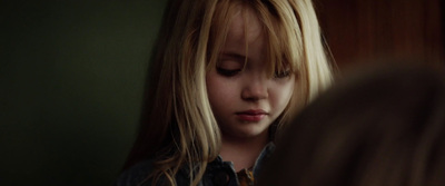 a young girl looking down at her cell phone