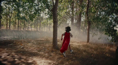 a girl in a red dress running through a forest