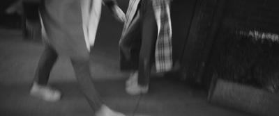 a black and white photo of two people walking