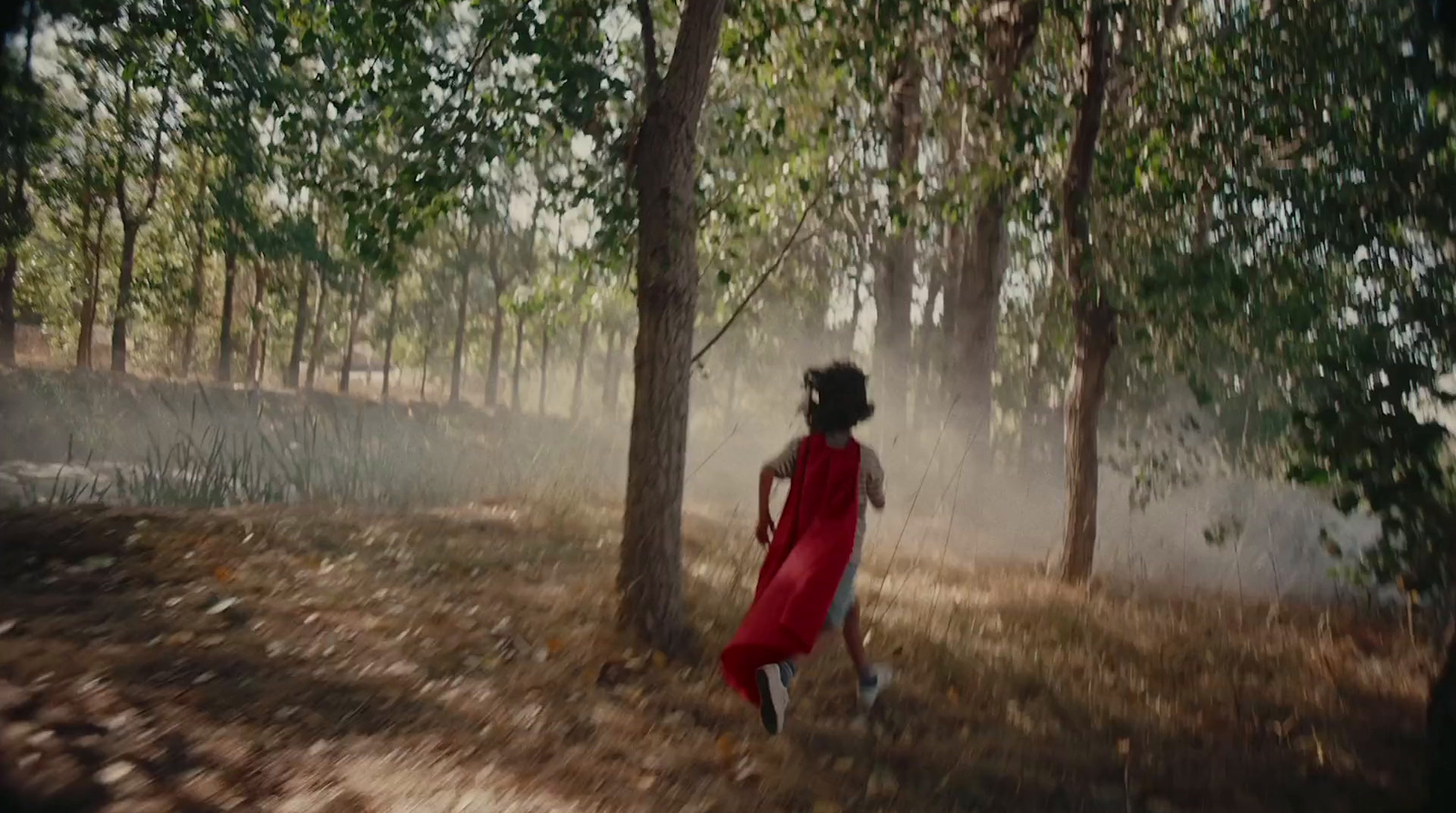 a woman in a red dress walking through a forest