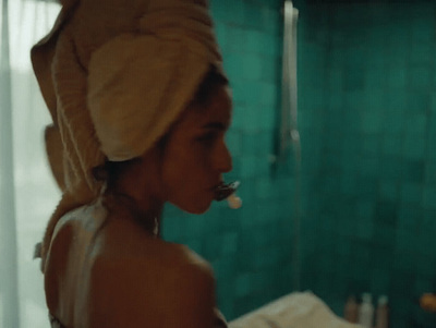 a woman with a towel on her head brushing her teeth