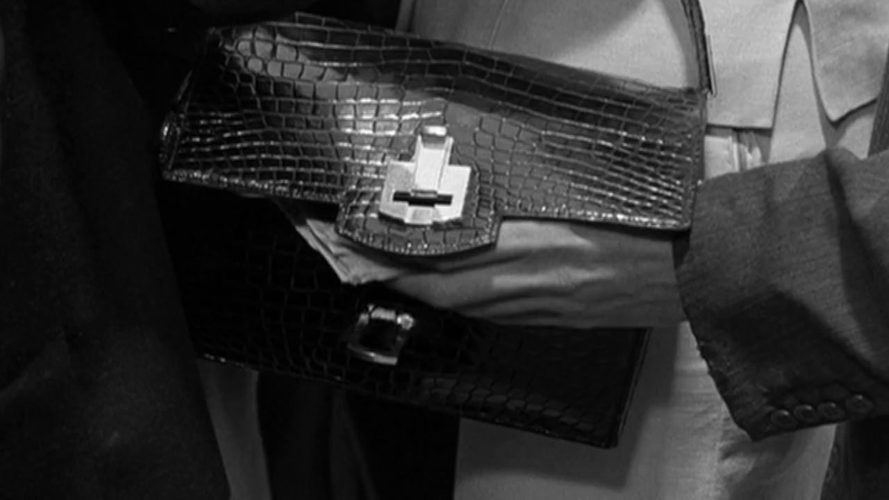 a black and white photo of a person holding a purse