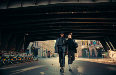 two women walking down a street under a bridge