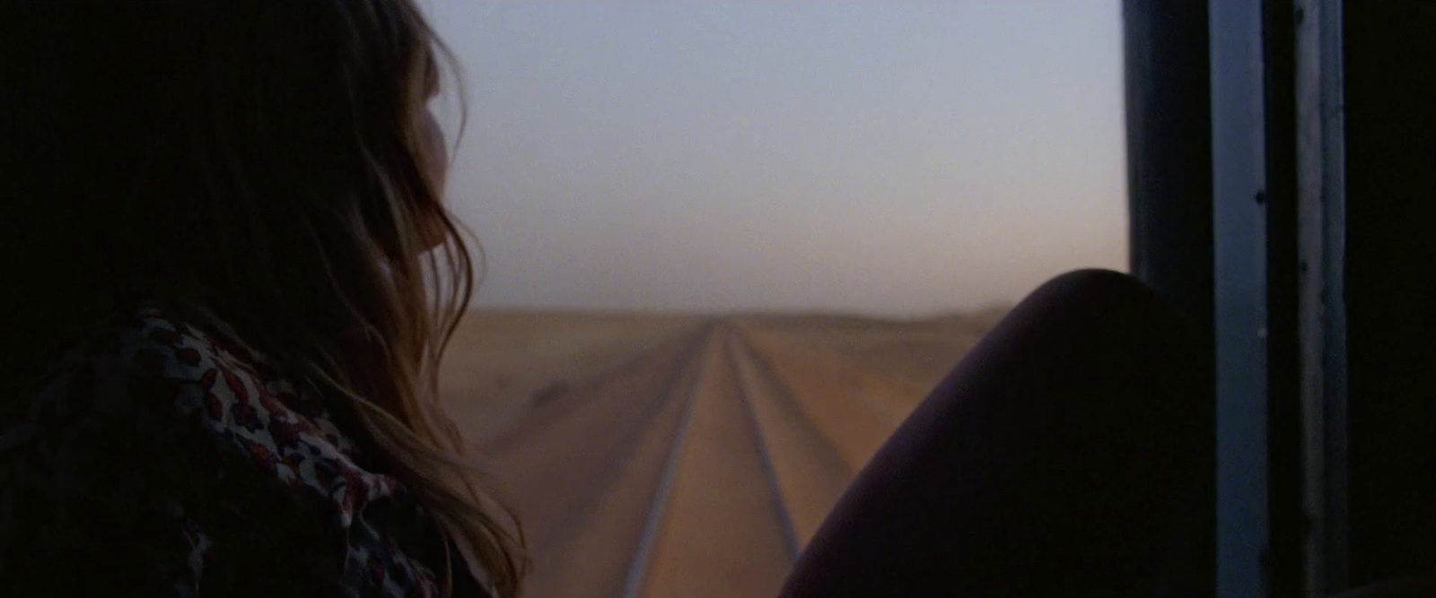 a woman looking out a train window at the desert