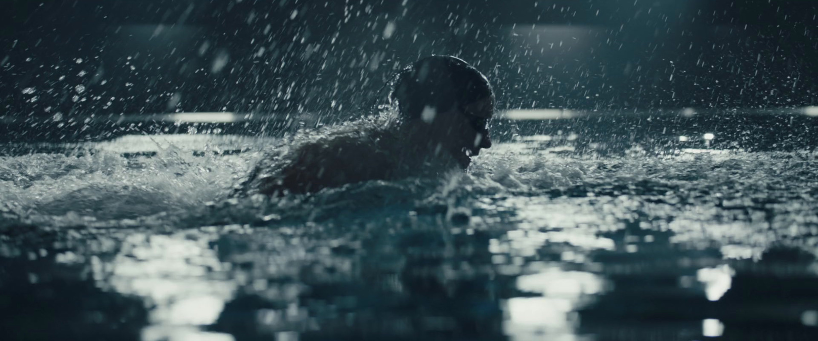 a man swimming in a pool in the rain