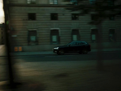 a black car driving down a street next to a tall building