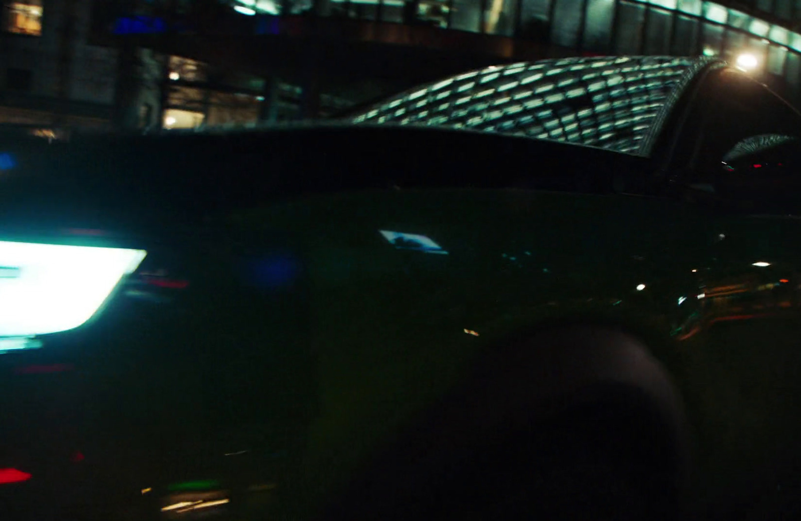 a close up of a car at night with a building in the background