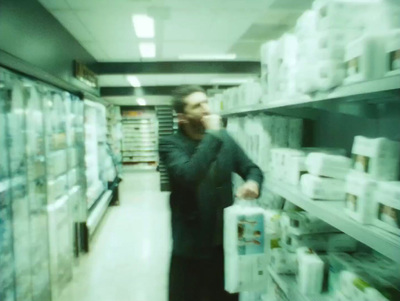 a man walking down a store aisle holding a box