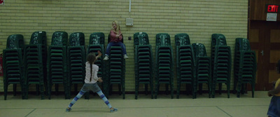 two girls playing a game of frisbee in a gym