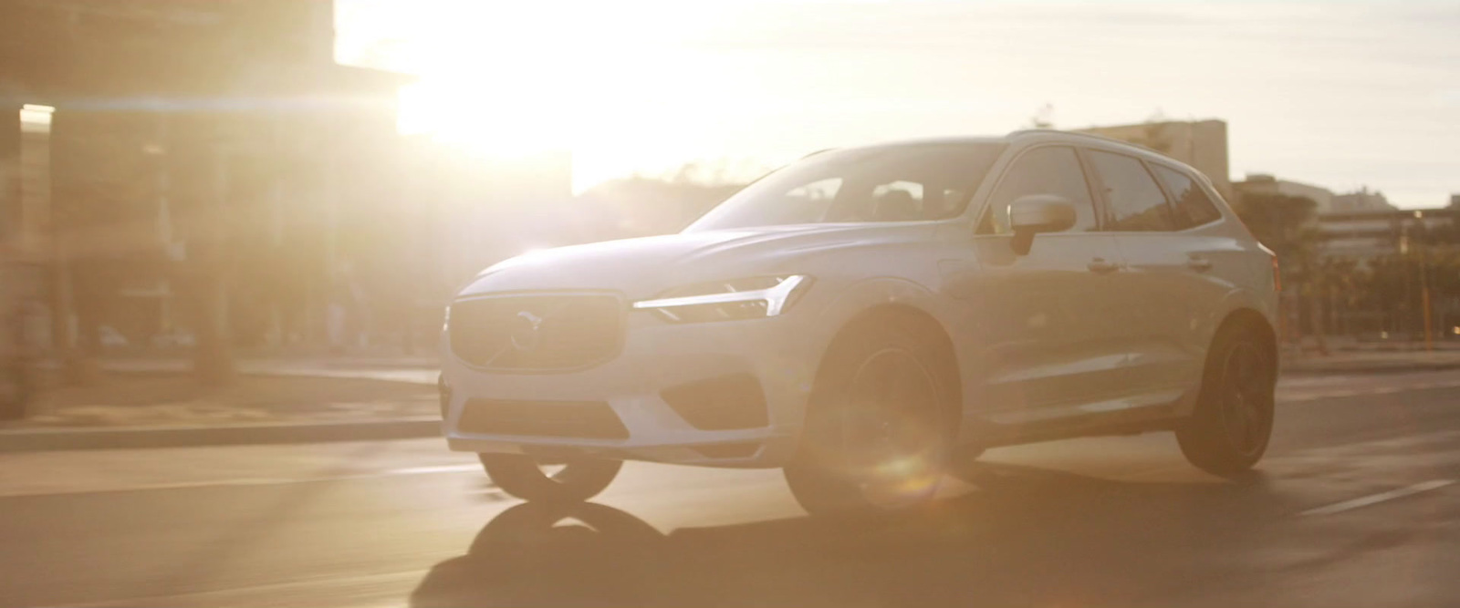 a white volvo car driving down a city street