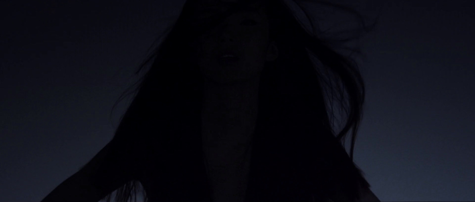 a woman with long hair standing in the dark