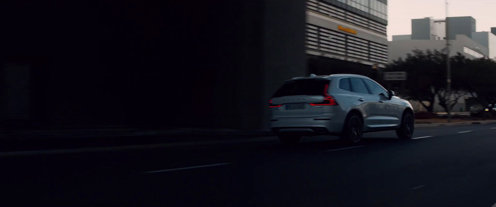 a white car driving down a street next to tall buildings