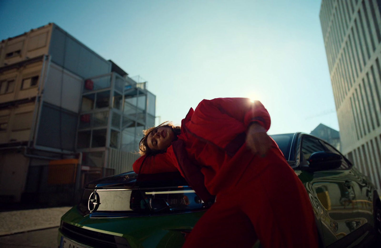 a person in a red outfit leaning on a car