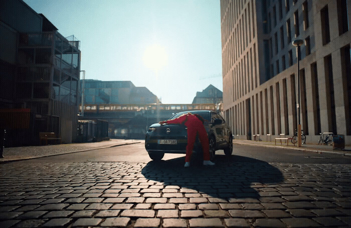 a person leaning on a car on a cobblestone street